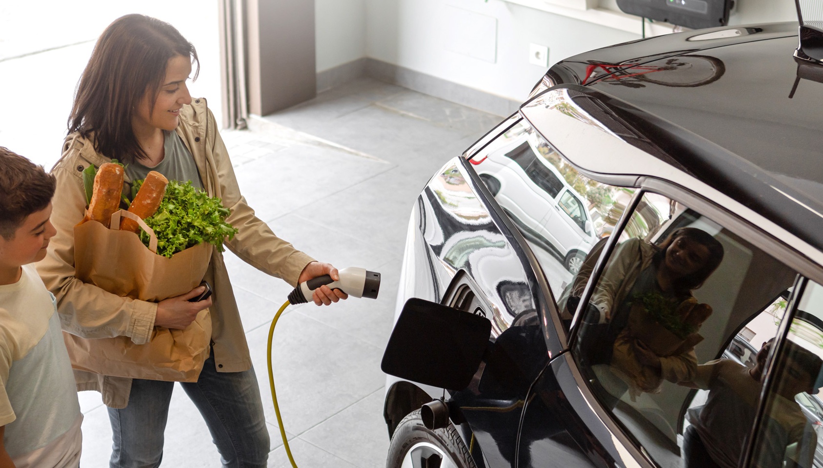 mother with kid charging an ev inside a home garage